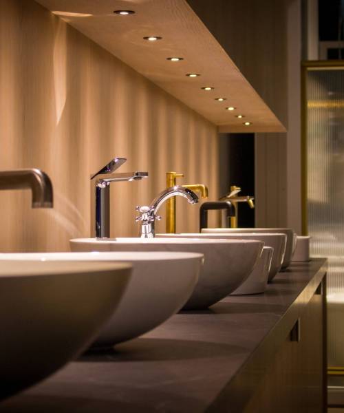 A closeup of basins and taps on display in a shop with dim lighting